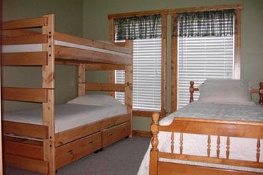 A room with bunk beds and two windows.